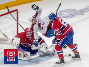A hockey player with his back to goal falls over the opposing goaltender as a defenceman looks on