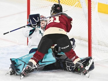 A hockey player slams into a goaltender on the ice.