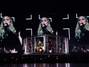 Madonna's face is projected onto three screens behind her stage performance.