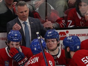 Montreal Canadiens coach Martin St Louis talks behind his bench to several players
