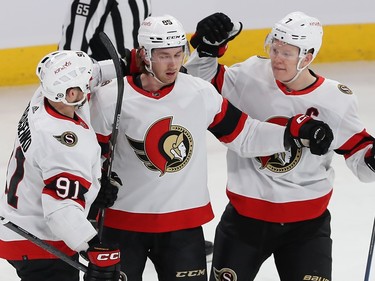 Ottawa Senators' Jake Sanderson celebrates with two other Senators players on the ice