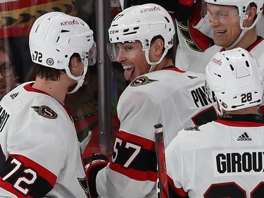 Ottawa Senators' Shane Pinto sticks out his tongue while surrounded by other Senators players