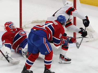 Ottawa Senators' Ridly Greig has the puck near his stick at the corner of the net, as Canadiens goaltender Jake Allen lies on his back in the crease