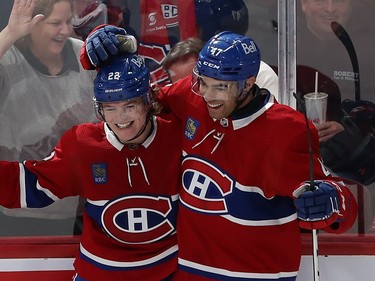 Montreal Canadiens' Cole Caufield and Jayden Struble smile and embrace each other along the boards