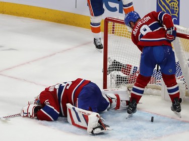 The puck rolls out of the net as Canadiens goalie Samuel Montembeault lies face-down on the ice and Mike Matheson stands in the crease