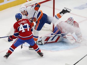 New York Islanders' Hudson Fasching leans forward and kicks his back skate into the air as he passes the side of the Montreal net during a game