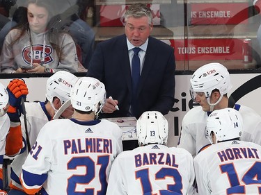 New York Islanders coach Patrick Roy speaks to his players from behind the bench