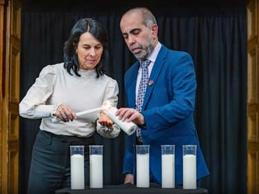 Valérie Plante and Samer Maizoub light one of six white candles on a table