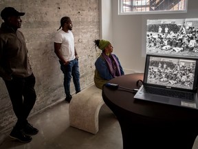 Three people look at black and white photographs on a screen