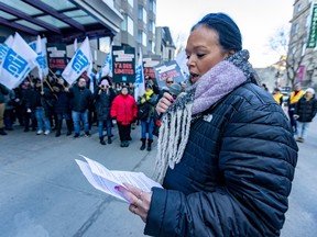 A woman reads a printed statement to people on a picket line.