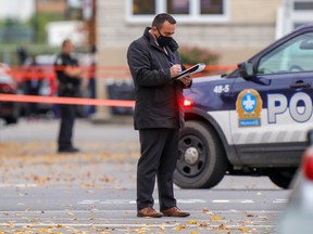A police investigator makes notes at the scene where two women were shot dead on Ontario St. in Montreal on Oct. 3, 2020.