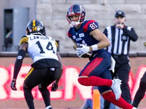 Alouettes' Austin Mack runs on the field carrying the football with a Tiger-Cats player in front of him