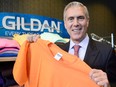 Glenn Chamandy holds up a T-shirt with a Gildan logo behind him