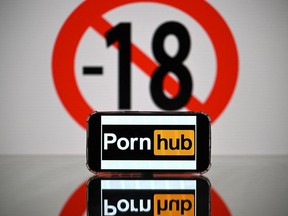 (FILES) This photograph taken on May 24, 2022 in Toulouse shows screens displaying a minor child sign and the logo of the pornographic site Pornhub.