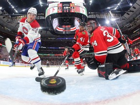A photo taken from inside the goal shows the puck in the crease with Canadiens' Juraj Slafkovsky on one side and a Blackhawks player and goalie on the other