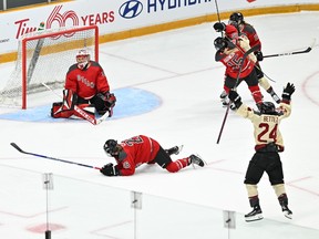 A Montreal PWHL player raises her arms in celebration looking toward the Ottawa net where the goaltender is on her knees