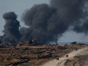 Israeli troops move out of the Gaza Strip as smoke rise over Gaza during Israeli bombardment.