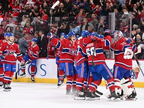 Canadiens players hug on the ice as fans cheer in the background