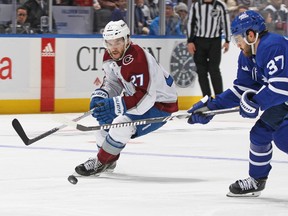 Avalanche's Jonathan Drouin is seen with the puck in front of him as he breaks past Maple Leafs' Timothy Liljegren during game Saturday night in Toronto.