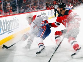 Canadiens' Brendan Gallagher plays the puck along the boards with New Jersey Devils' Colin Miller right behind him, both players making snow with their skates