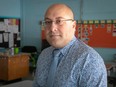 Joe Ortona, chair of the English Montreal School Board, stands in a classroom, with desks behind him.