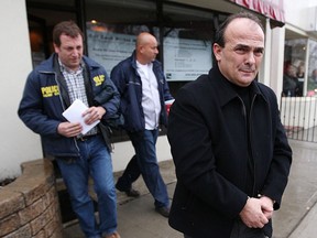 Vincenzo "Jimmy" DeMaria, right, is led to a police cruiser after being arrested in Toronto on April 20, 2009.