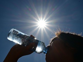 Photo shows unidentified person drinking from a water bottle on a blazing sun.