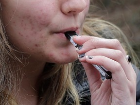 Closeup of the bottom of a young girl's face. She is vaping.