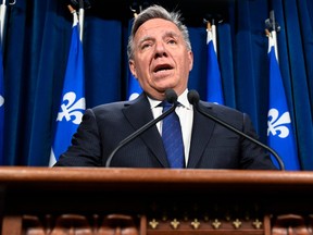 Quebec Premier François Legault is shown standing at a lectern and responding to reporters questions at a news conference on April 25, 2023.