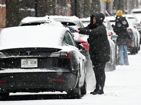 People clear snow from their cars during heavy snowfall in Montreal, Sunday, Dec. 3, 2023.