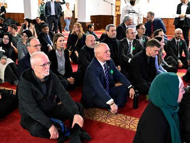 A large group of people sit on the floor inside a mosque