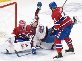 Colorado Avalanche's Ross Colton falls between Canadiens' David Savard and goalie Jake Allen in front of the crease