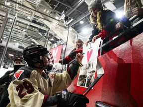 Montreal's Marie-Philip Poulin (29) signs a fan's sign before a PWHL hockey game between Ottawa and Montreal, in Ottawa, Tuesday, Jan. 2, 2024.