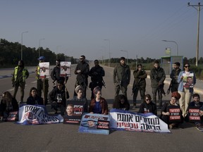 Relatives and friends of hostages held in the Gaza Strip by the Hamas militant group sit on the road next to Kerem Shalom border crossing.