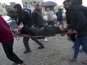 Palestinians bring a woman wounded in the Israeli bombardment of the Gaza Strip to a hospital in Deir al Balah on Saturday, Jan. 13, 2024.