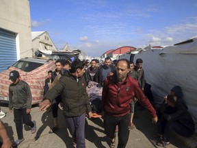 Palestinians carry the a body of a person killed in the Israeli bombardment at a building of an UNRWA vocational training centre.