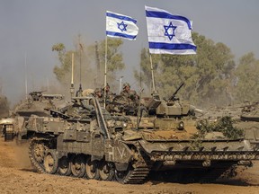Israeli army vehicles arrive at a staging area after combat in the Gaza Strip in southern Israel, Saturday, Dec. 30, 2023.