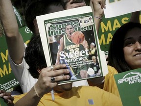 A George Mason University fan holds up the cover of Sports Illustrated magazine at a send off for the team on March 29, 2006, in Fairfax, Va. The publisher of Sports Illustrated has notified employees it is planning to lay off a significant portion — possibly all — of the outlet's staff after its license to use the iconic brand's name in print and digital was revoked.