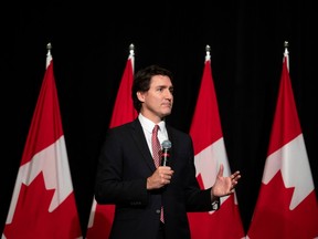 Prime Minister Justin Trudeau speaks in front of a row of Canadian flags.