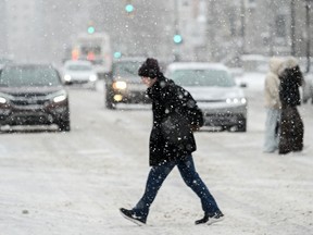 A person crosses a street as snow falls in Montreal on Jan. 7, 2024.