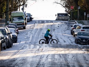 A cyclist crosses a steep, snowy street.