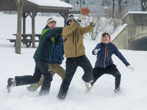 Liam McGreevy, left, Lucas Acerenza and Porter Jones play football in the snow at Baker Park on Friday, Jan. 19, 2024, in Frederick, Md. The three Frederick High School students had the day off as Frederick County schools were closed.