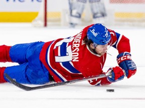 Canadiens' Josh Anderson attempts to play the puck while lying on his side on the ice