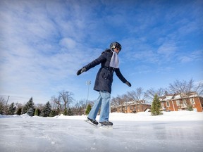 A woman skates on an outdoor rink in a residential area.