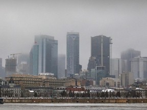 Low-lying clouds partly obscure the tops of tall buildings on the Montreal skyline on a grey winter day.