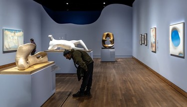 A visitor reads the info for Henry Moore's sculpture Reclining Figure Bone, 1975, at the MMFA on Feb. 6, 2024.