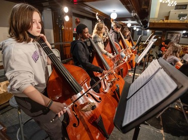 A row of students practice on double basses.