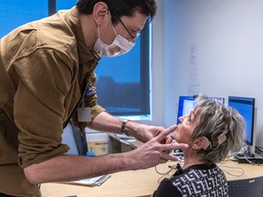 A doctor is bending over to speak with a seated woman. Her cochlear implants are visible.
