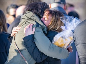 Two women hug at a memorial for victims of the Laval daycare bus crash on the one-year anniversary of the tragedy.