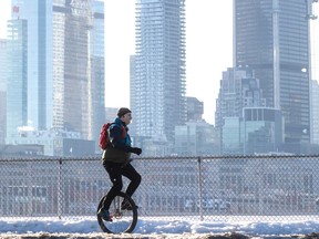 A man on a unicycle with the Montreal skyline in the background.